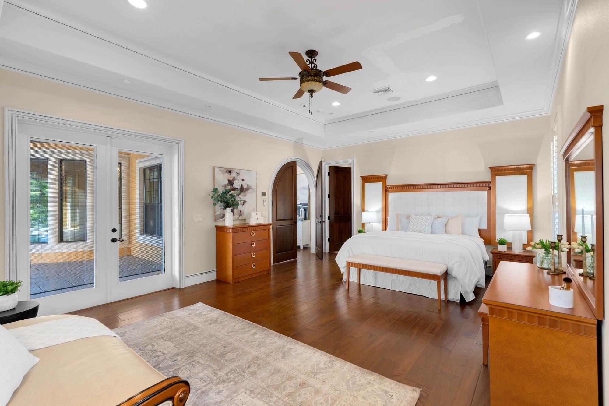 A primary bedroom suite with a tray ceiling and private access to the terrace